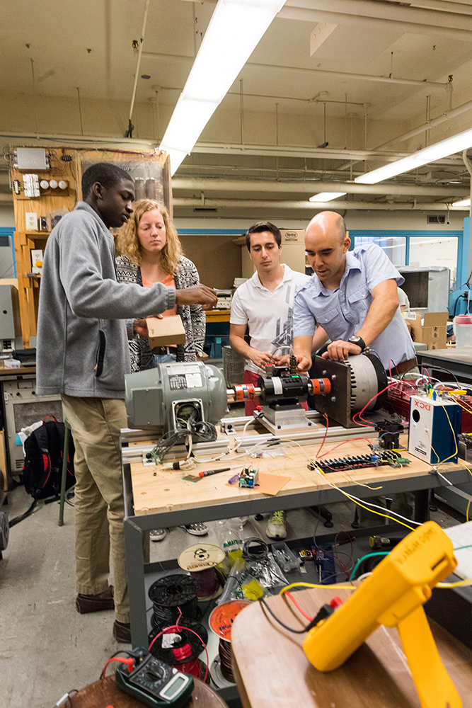 Left to right: UROP students Daniel Vignon ’17, Taylor V’Dovec ’19, and Juan De Jesus ’17, and MITEI postdoc Claudio Vergara adjust a torque and angular speed sensor, which is mounted on a shaft between electrical machines operated as a motor and a generator in their lab-scale model of a power system. The sensor will be used to estimate the electromechanical parameters of the machines. Photo: Justin Knight
