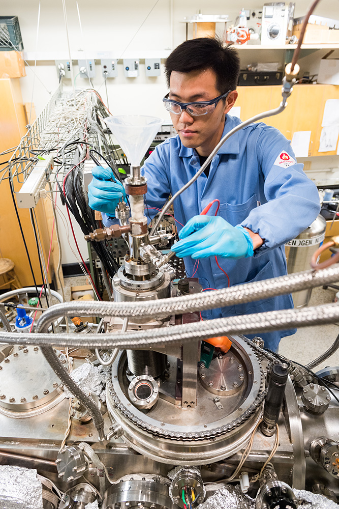Graduate student Qing Liu of chemistry prepares for an experiment examining fundamental chemical reactions that occur on a crystal designed to catalyze fuel gasification in a Fischer-Tropsch system. Here he performs a routine check of the connection between the thermocouple leads and the sample crystal to ensure reliable readings of reaction temperatures during the tests. Photo: Justin Knight